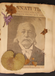 Photograph of Rabbi Isaac M. Wise retrieved from a scrapbook compiled of his life and death. The image is attached the the paper and covered with dried leaves and flowers.