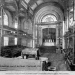 Image of the inside of Mikveh Israel, including central bima, ark, and separated, gender-based seating on different levels.