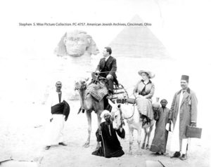 Black and white photograph of Rabbi Stephen S. Wise on a camel surrounded by a group of people. 